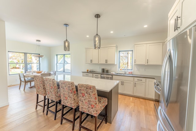 kitchen featuring pendant lighting, a breakfast bar, a center island, white cabinets, and stainless steel appliances