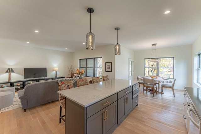 kitchen with gray cabinetry, decorative light fixtures, light wood-type flooring, and built in microwave