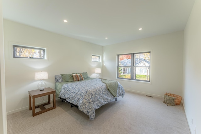 bedroom with multiple windows and light carpet