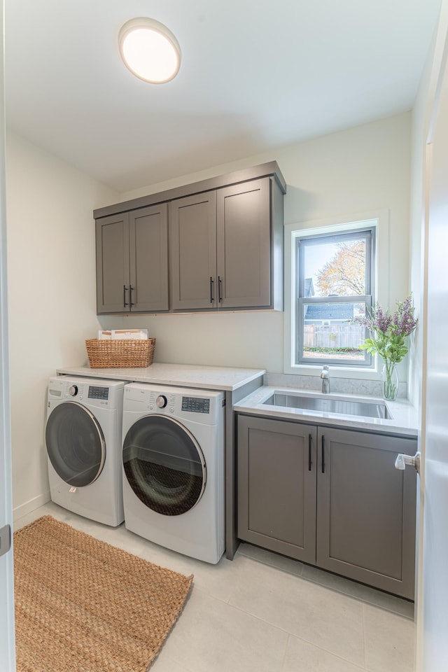 laundry area with cabinets, independent washer and dryer, light tile patterned floors, and sink