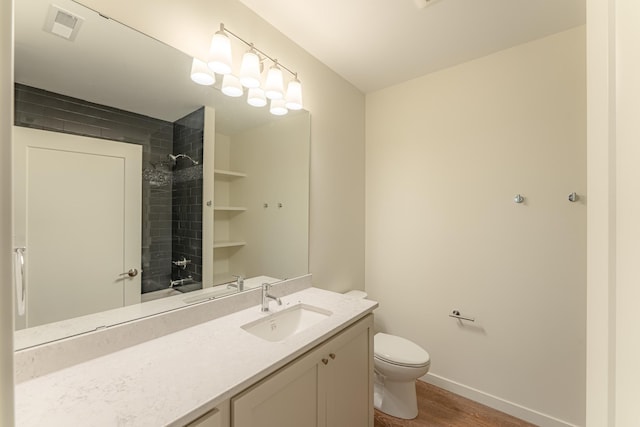 bathroom featuring a tile shower, vanity, hardwood / wood-style flooring, and toilet