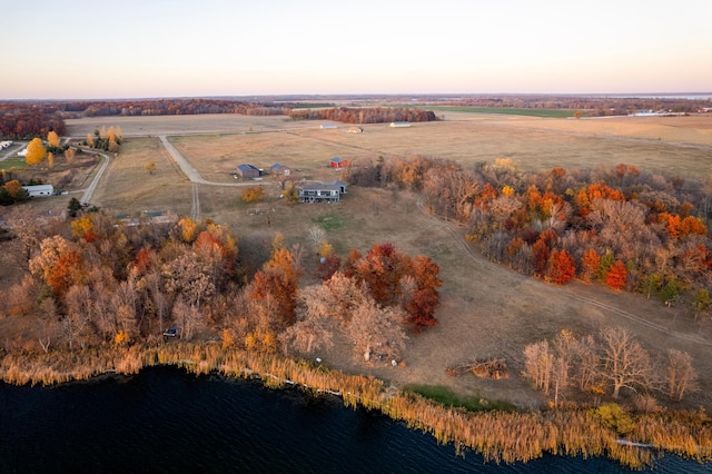 aerial view at dusk featuring a rural view and a water view