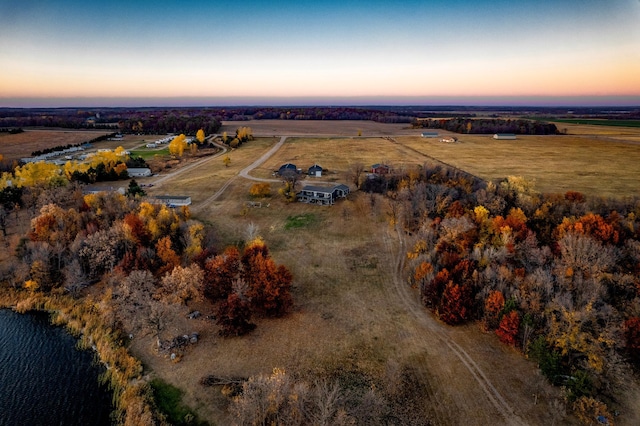 aerial view at dusk featuring a rural view and a water view