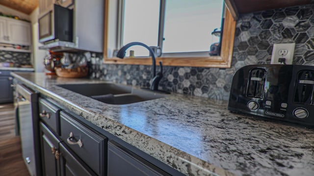 kitchen with dishwasher, sink, light stone counters, and decorative backsplash