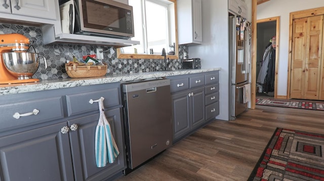 kitchen with sink, light stone counters, tasteful backsplash, appliances with stainless steel finishes, and dark hardwood / wood-style floors