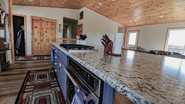 kitchen featuring appliances with stainless steel finishes, blue cabinets, lofted ceiling, wood ceiling, and light stone countertops