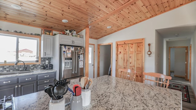 kitchen featuring gray cabinets, high end fridge, sink, and light stone countertops