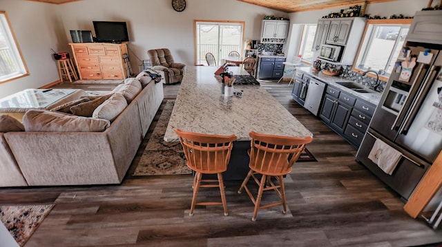 kitchen featuring a breakfast bar, white cabinetry, sink, stainless steel appliances, and dark wood-type flooring