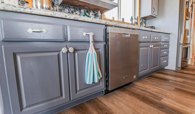 kitchen with dark hardwood / wood-style floors, dishwashing machine, light stone countertops, and gray cabinetry