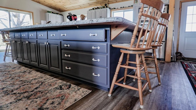 kitchen with a breakfast bar, wooden ceiling, and dark hardwood / wood-style flooring