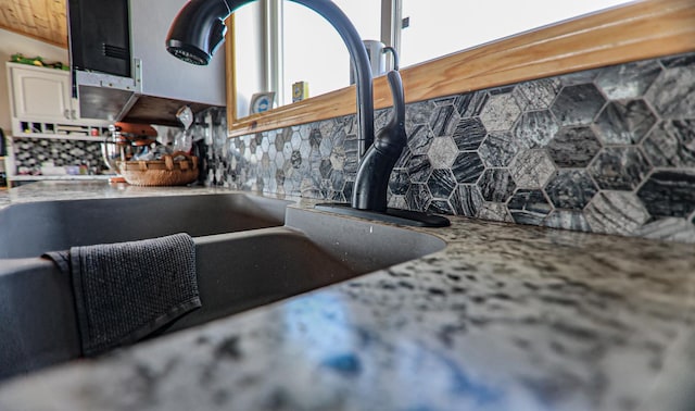 details featuring white cabinetry, backsplash, and sink