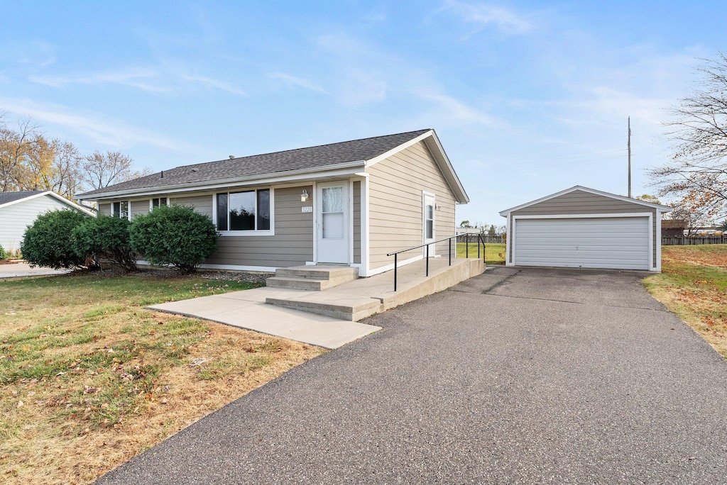 single story home featuring a front lawn, a garage, and an outdoor structure