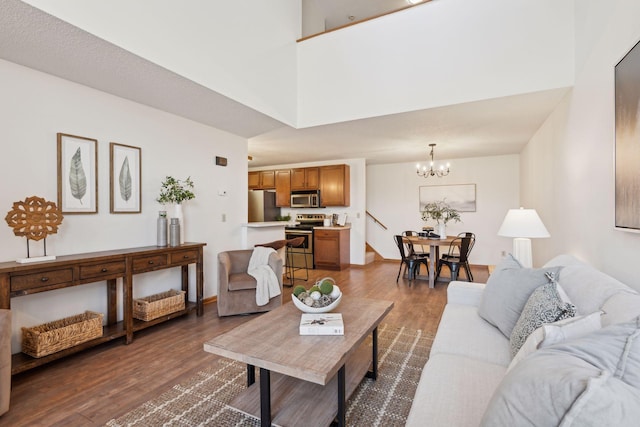 living room featuring an inviting chandelier, dark hardwood / wood-style floors, and a high ceiling