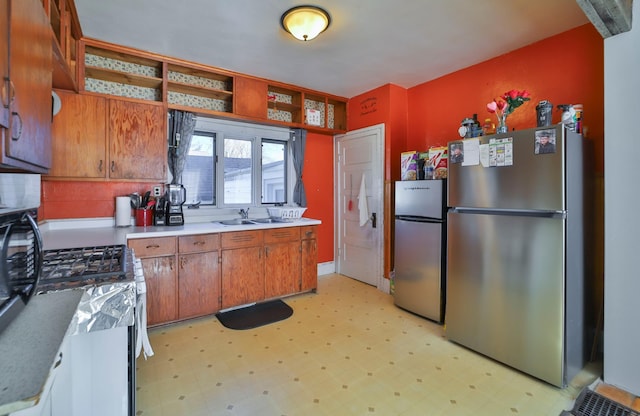 kitchen featuring stainless steel fridge, white range with gas stovetop, and sink