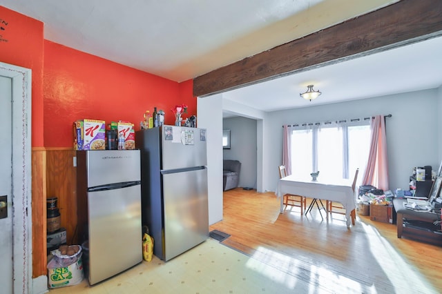 kitchen with stainless steel refrigerator, light hardwood / wood-style flooring, and beamed ceiling