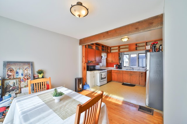 dining room with beam ceiling and light hardwood / wood-style flooring