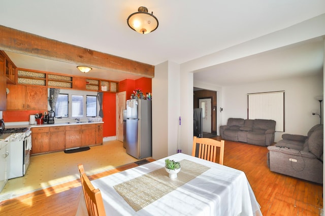 dining space with beamed ceiling, light hardwood / wood-style flooring, and sink