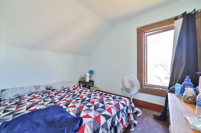 bedroom featuring multiple windows, vaulted ceiling, and dark colored carpet