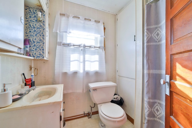 bathroom with vanity, toilet, and tile walls