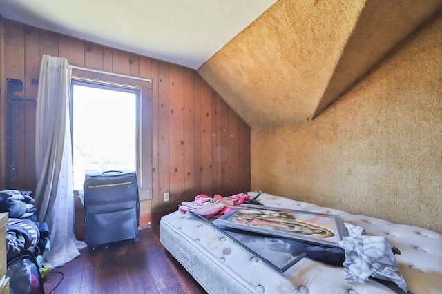 bedroom featuring wood walls, dark wood-type flooring, and lofted ceiling