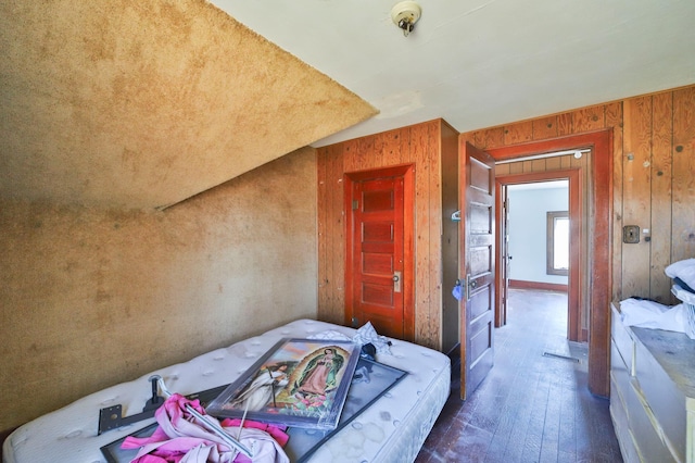 bedroom with dark hardwood / wood-style floors and wood walls