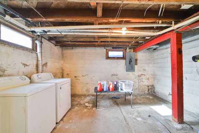 basement with a healthy amount of sunlight, washing machine and dryer, and electric panel