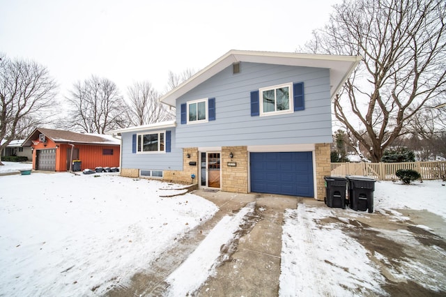 tri-level home featuring an attached garage and fence