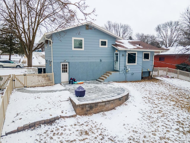 snow covered property with a gate, a fenced backyard, and stucco siding