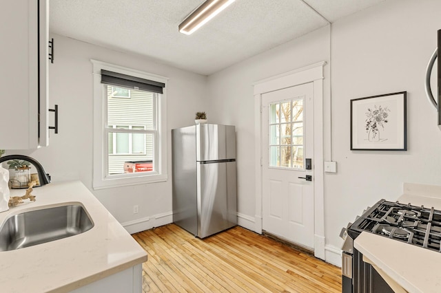 kitchen featuring a sink, appliances with stainless steel finishes, a wealth of natural light, and light countertops