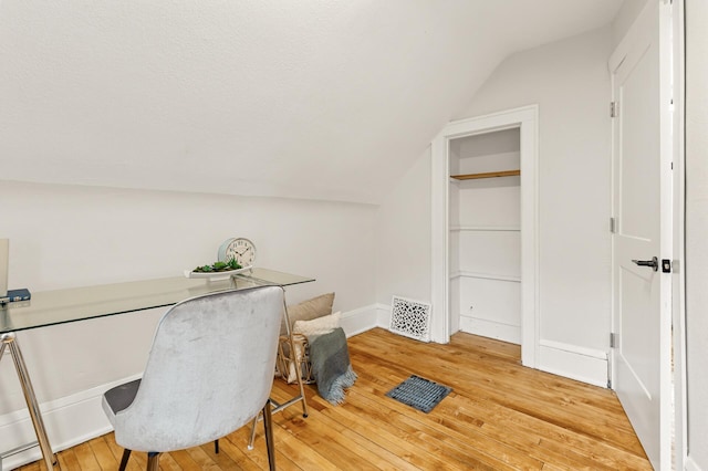 home office featuring visible vents, light wood finished floors, and lofted ceiling
