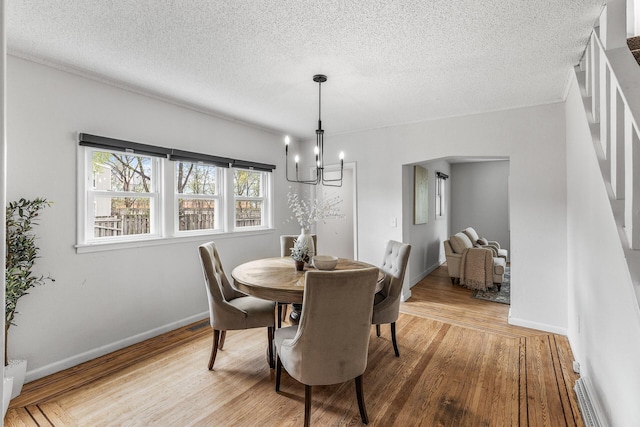 dining room with baseboards, a notable chandelier, a textured ceiling, and wood finished floors