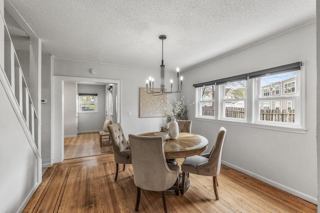 dining area featuring a notable chandelier, baseboards, plenty of natural light, and wood finished floors