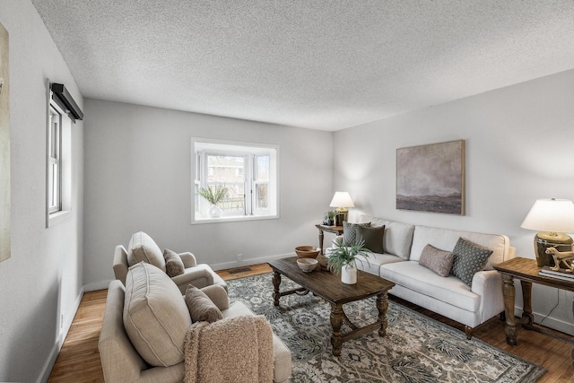living room with baseboards, a textured ceiling, and wood finished floors