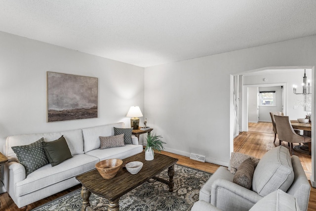 living area with a textured ceiling, baseboards, visible vents, and light wood-style floors