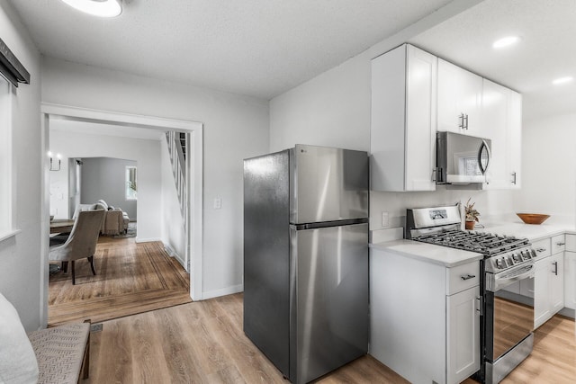 kitchen with light wood finished floors, stainless steel appliances, white cabinetry, light countertops, and recessed lighting