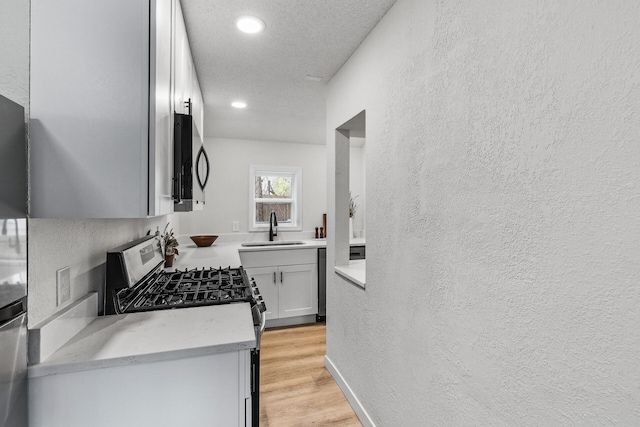 kitchen featuring recessed lighting, appliances with stainless steel finishes, a sink, and a textured wall