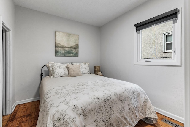 bedroom with wood finished floors, visible vents, and baseboards