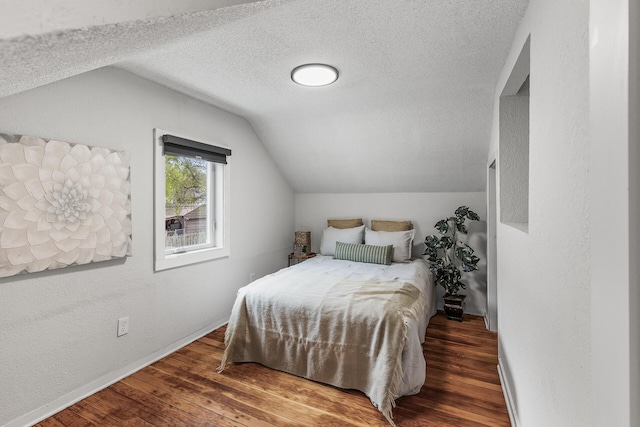 bedroom featuring lofted ceiling, a textured ceiling, and wood finished floors