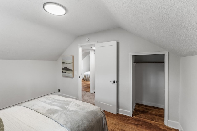 bedroom featuring lofted ceiling, baseboards, a textured ceiling, and wood finished floors