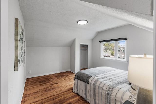 bedroom featuring a closet, wood finished floors, a textured ceiling, and vaulted ceiling