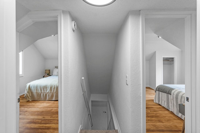 bedroom featuring a textured wall, baseboards, and wood finished floors