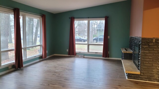 unfurnished living room featuring plenty of natural light and dark wood-type flooring