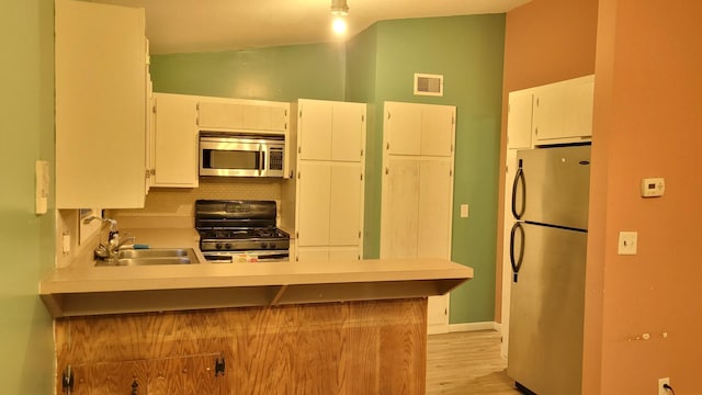 kitchen featuring kitchen peninsula, appliances with stainless steel finishes, tasteful backsplash, sink, and white cabinets