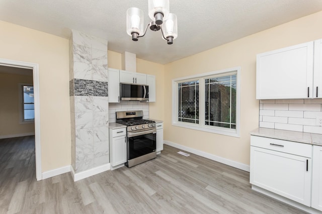 kitchen featuring white cabinetry, appliances with stainless steel finishes, a textured ceiling, and light wood-type flooring