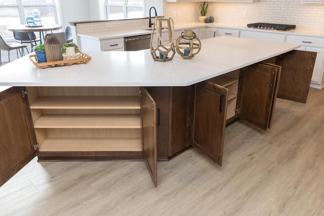 kitchen featuring light hardwood / wood-style floors, sink, a kitchen island, white cabinets, and decorative backsplash