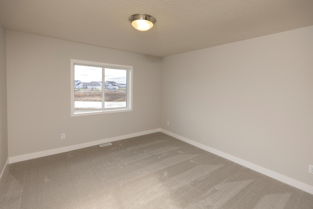 carpeted spare room featuring a textured ceiling