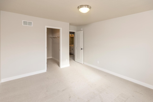 unfurnished bedroom featuring light colored carpet, a closet, and a spacious closet