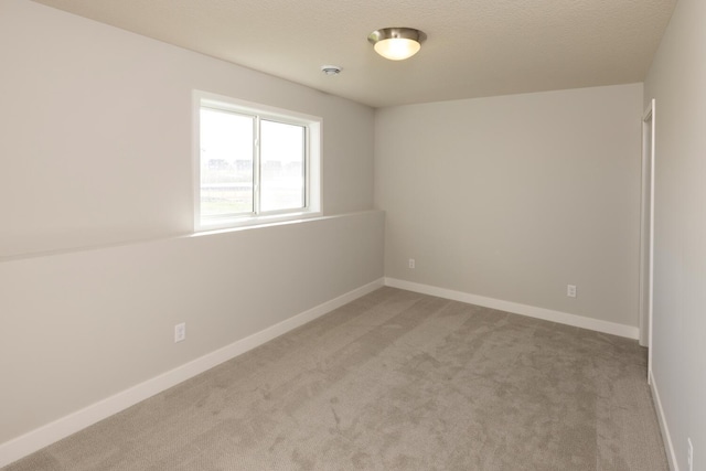 empty room with a textured ceiling and light carpet