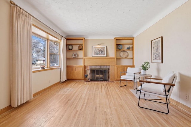 living area featuring baseboards, light wood-style flooring, and a fireplace