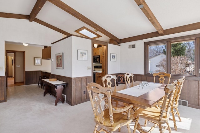 dining room with vaulted ceiling with beams, visible vents, a wainscoted wall, and light carpet